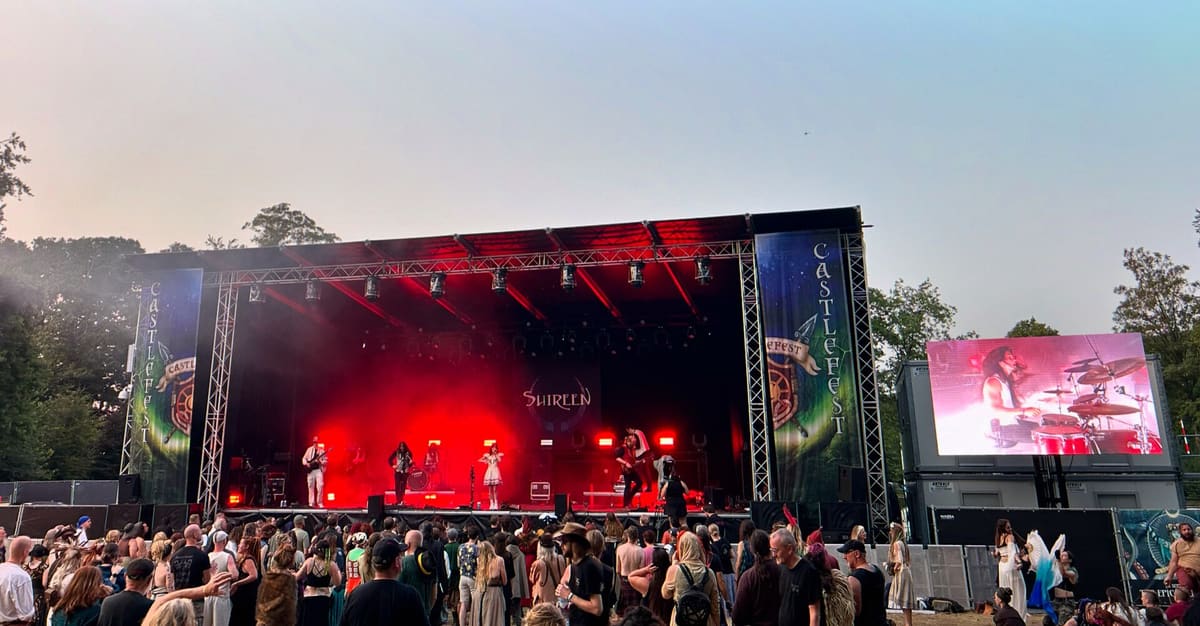 Outdoor concert stage with a large LED screen showing the performance to the audience